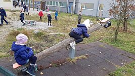 Kinder sitzen auf Wippe im Schulgarten